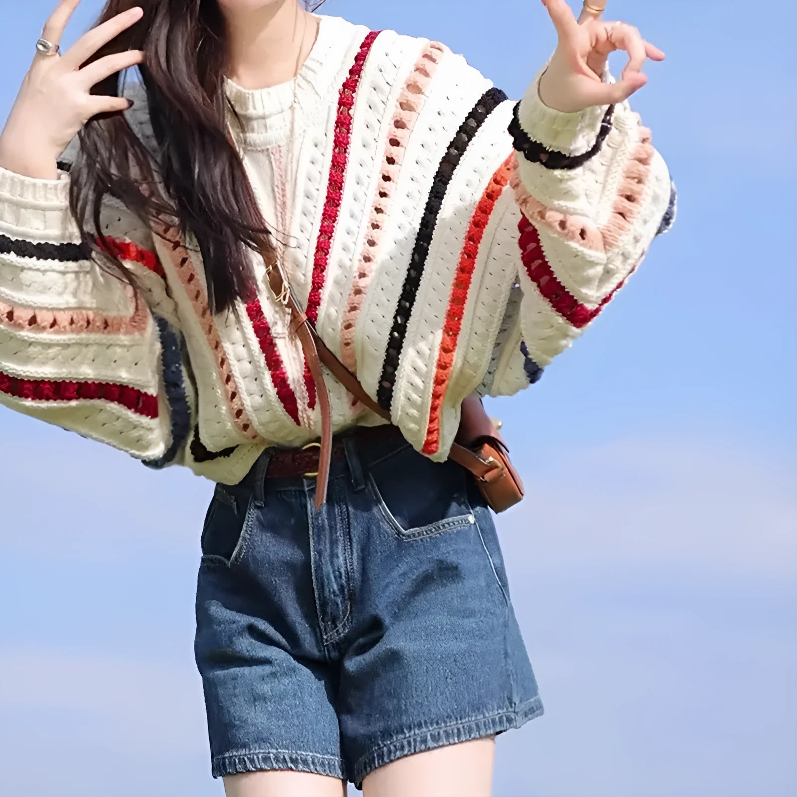 Retro rainbow striped loose fit sweater with batwing sleeves on a hanger.