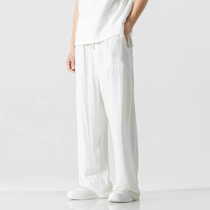 Man wearing beige bamboo fibre cropped trousers with a drawstring waist and straight legs.