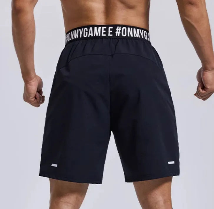 Man wearing loose black shorts with letter print, elastic waist, for sports and workout.