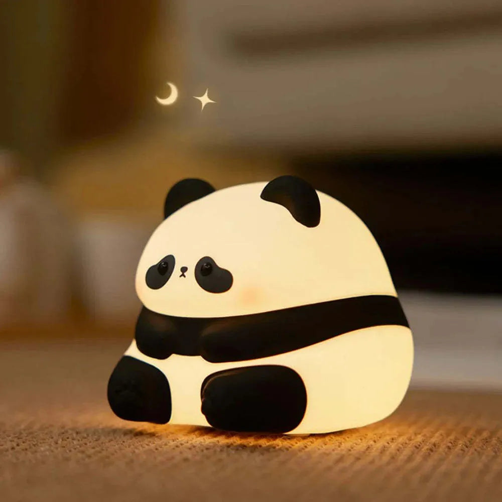 Cartoon panda head shaped silicone night light for children on a bedside table.