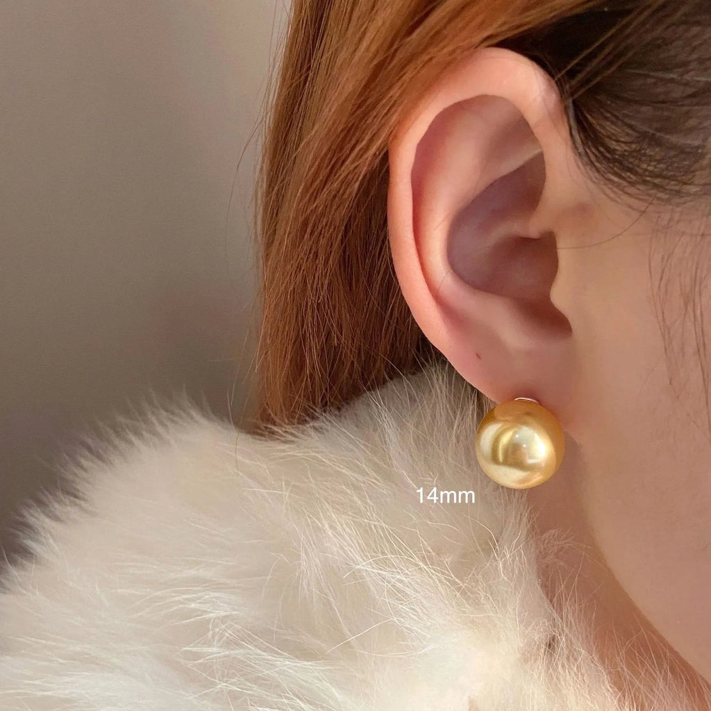 A pair of large geometric pearl stud earrings with a retro design on a silver setting.