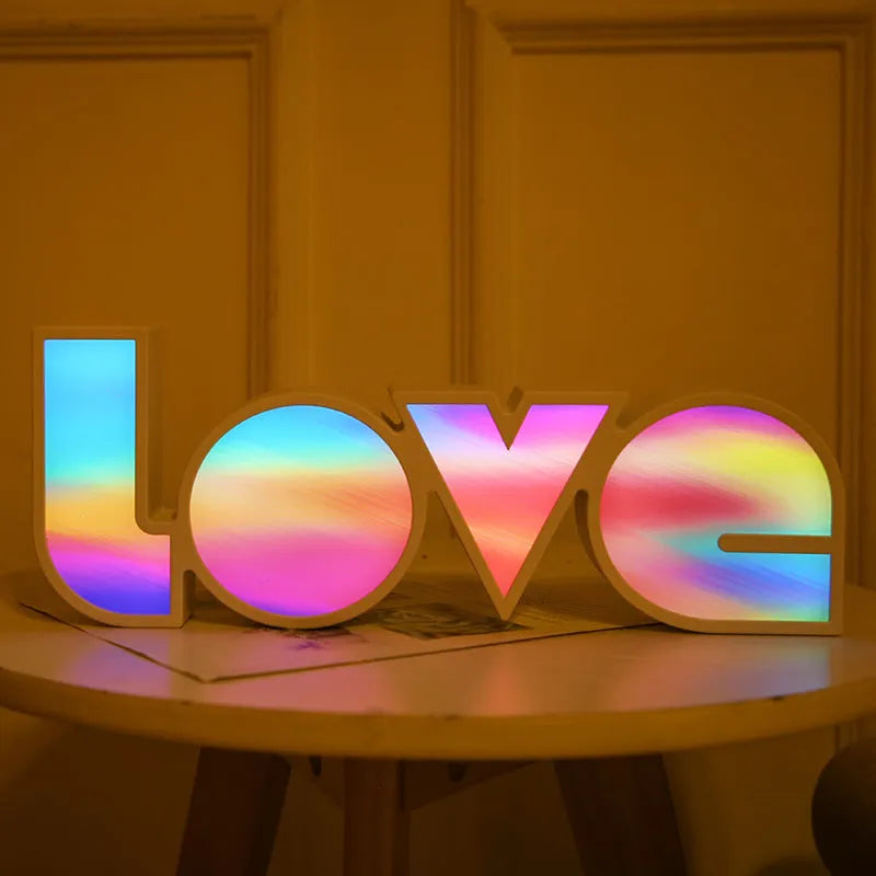 Rainbow coloured LED LOVE word light for Valentine's Day and wedding decoration on a table.