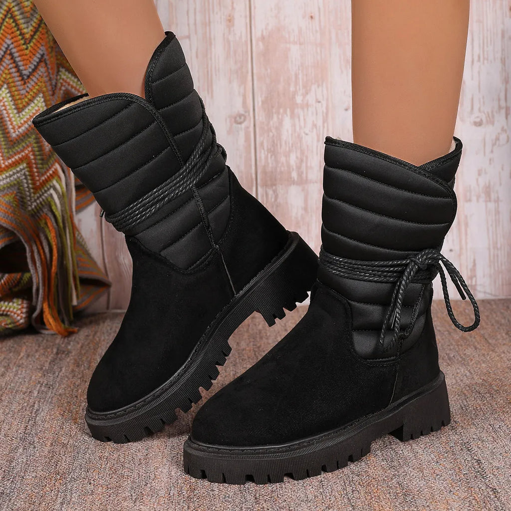 Black women's high-top snow boots with a chunky heel and lace-up front on a grey background.