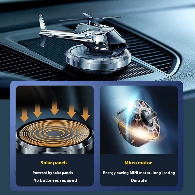 Silver metal solar-powered helicopter car air freshener clipped to a vehicle air vent, with rotating blades.