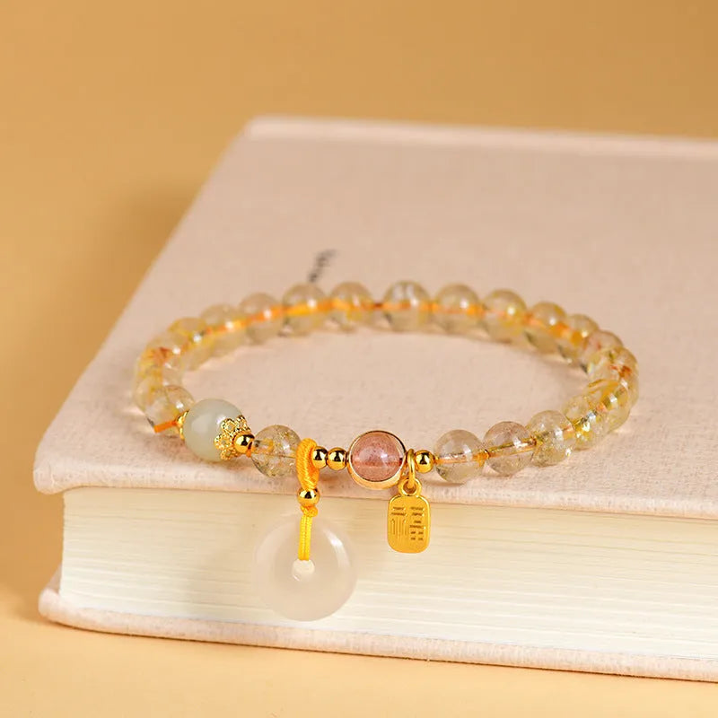 Gold rutilated quartz bracelet with a peace buckle pendant and geometric safety clasp.