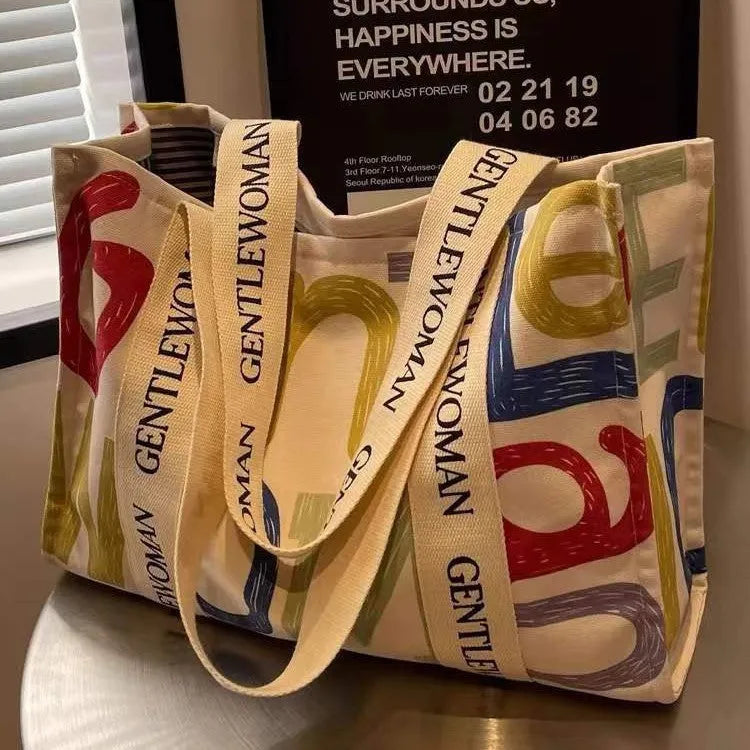 Large canvas women's tote bag with printed design, shown in shopping and travel use contexts.