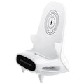 White mini chair-shaped wireless phone charger on a desk, with phone seated on it.