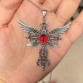 Close-up of a silver-coloured geometric pendant with wing details and a central cross on a chain.