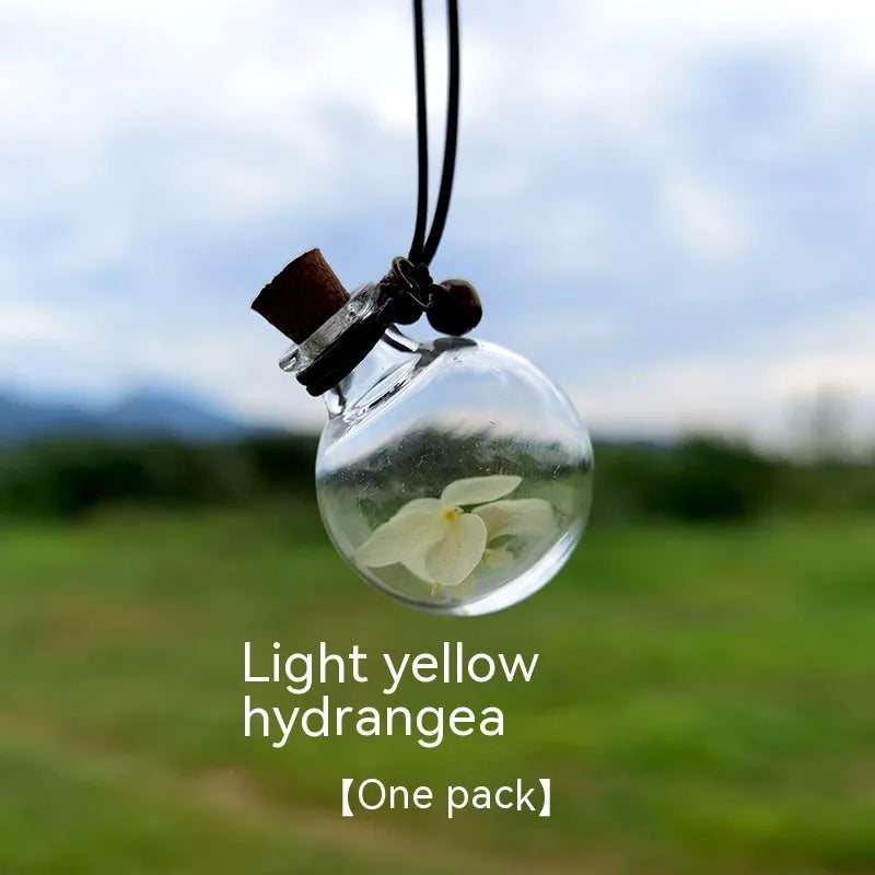 Glass car perfume pendant with preserved flowers inside, shown in a selection of different floral colours.