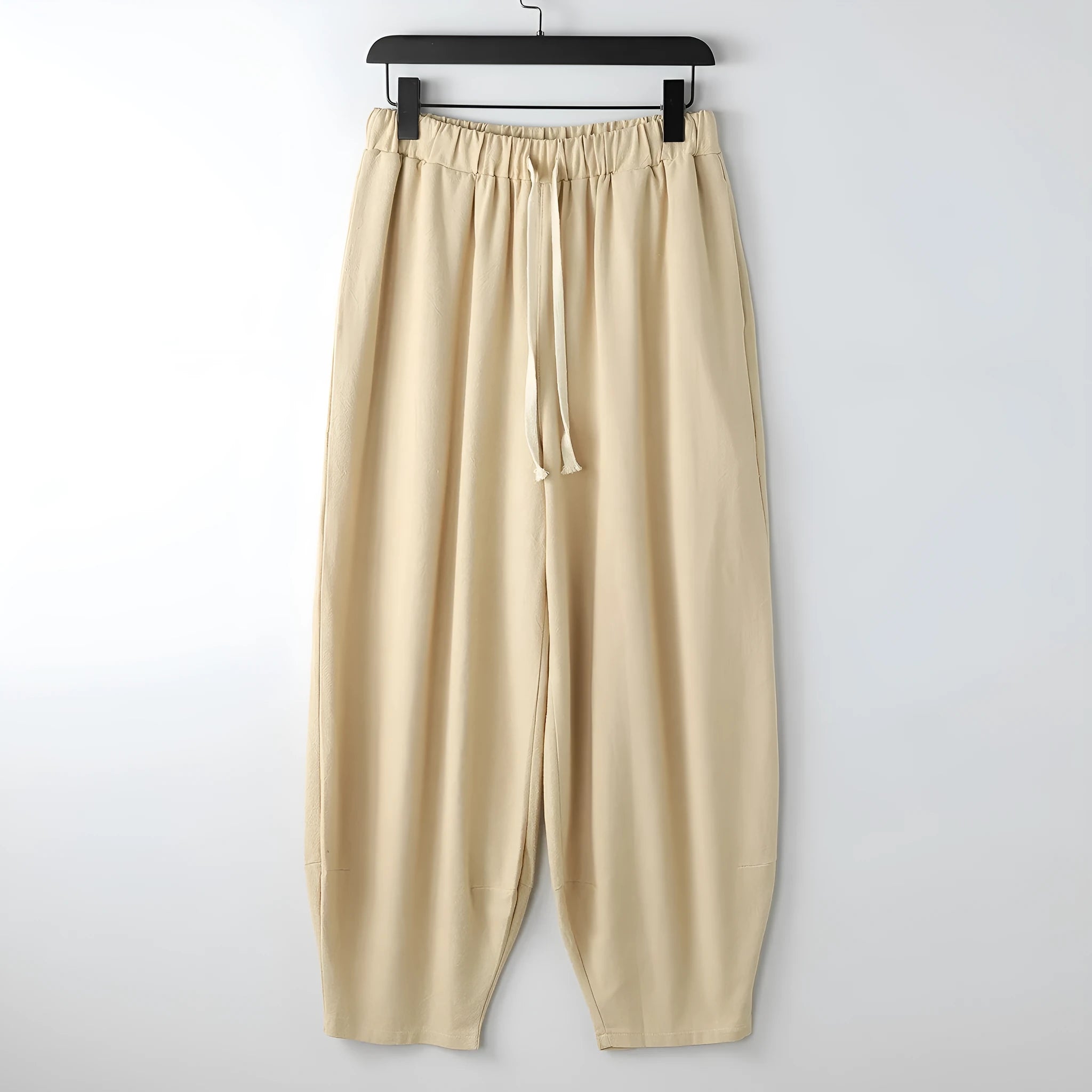 Man wearing loose grey linen harem pants with ankle ties, showing tapered leg fit for larger builds.