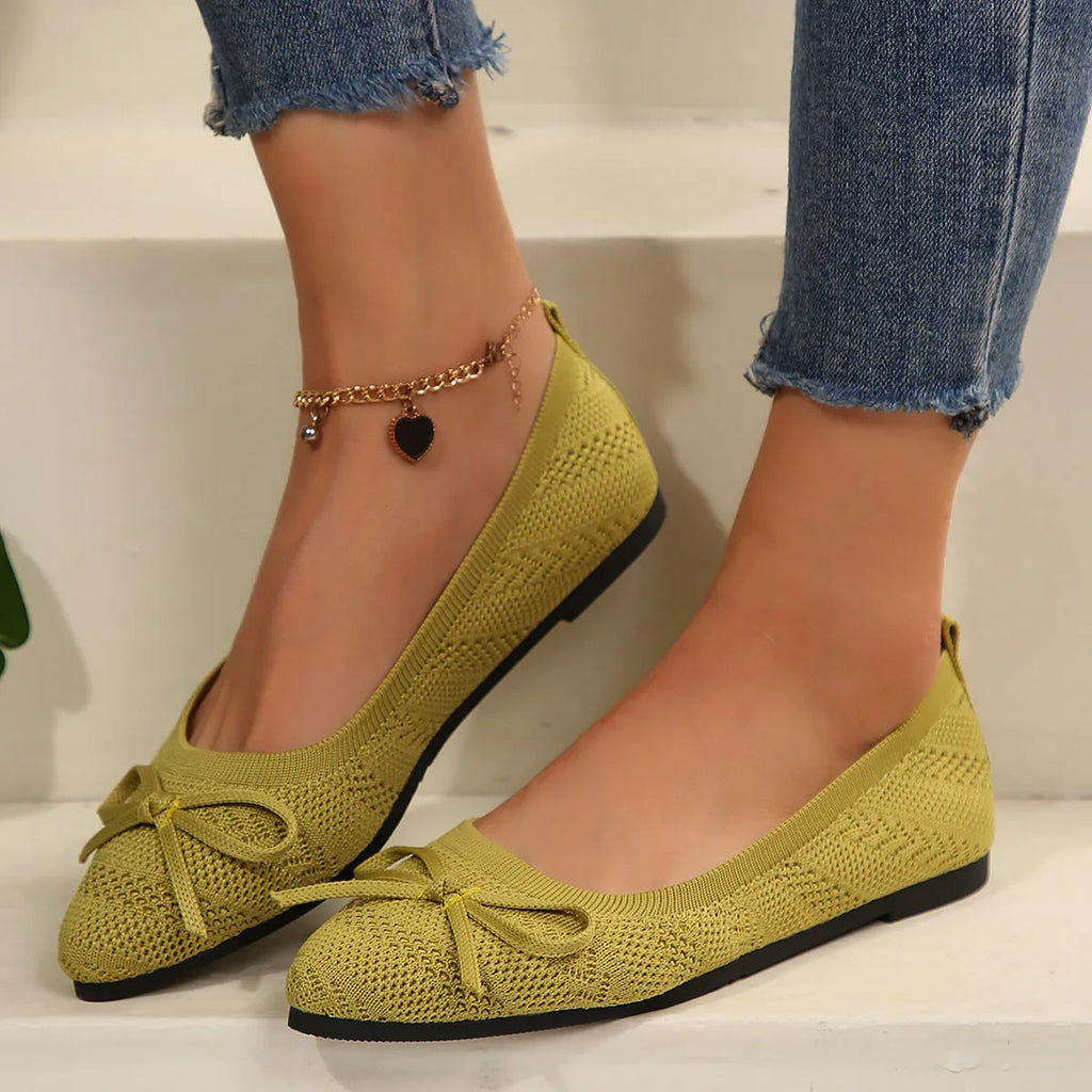 Women's knitted flat shoes with a bow detail and pointed toe in various colours on a plain background.