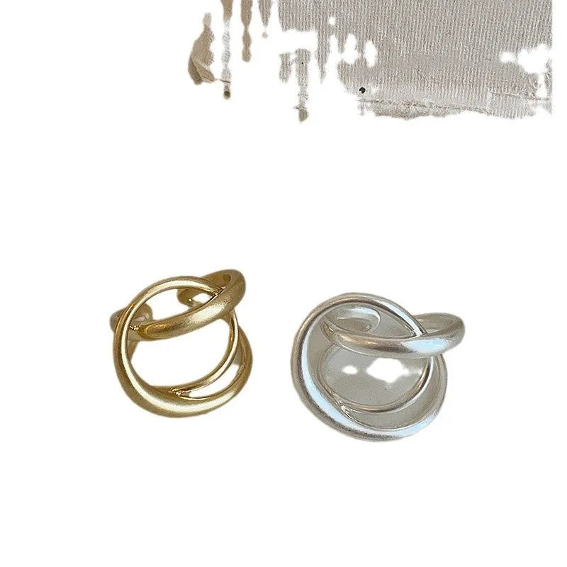 Geometric open ring with interlaced metal design and matte finish in gold colour.