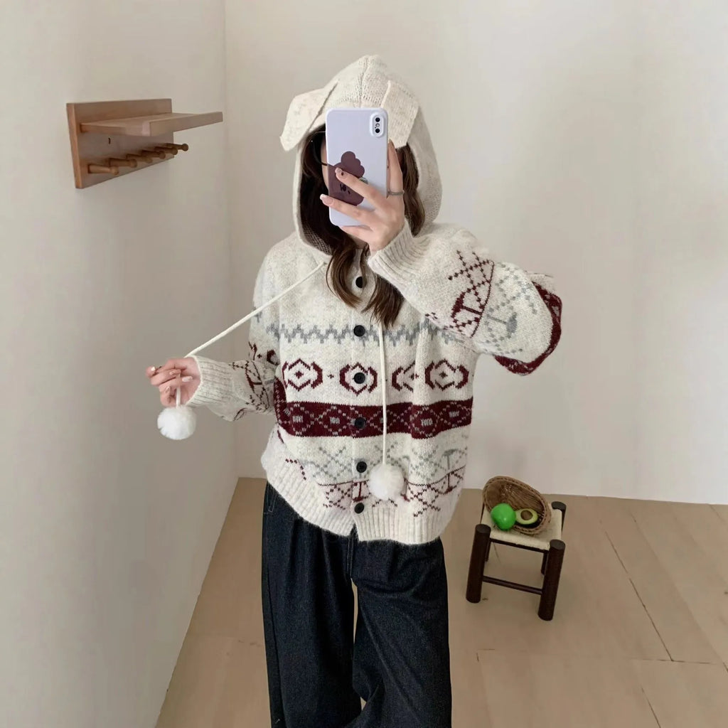 Woman wearing a beige loose-fit brocade sweater coat with a geometric pattern and long sleeves.