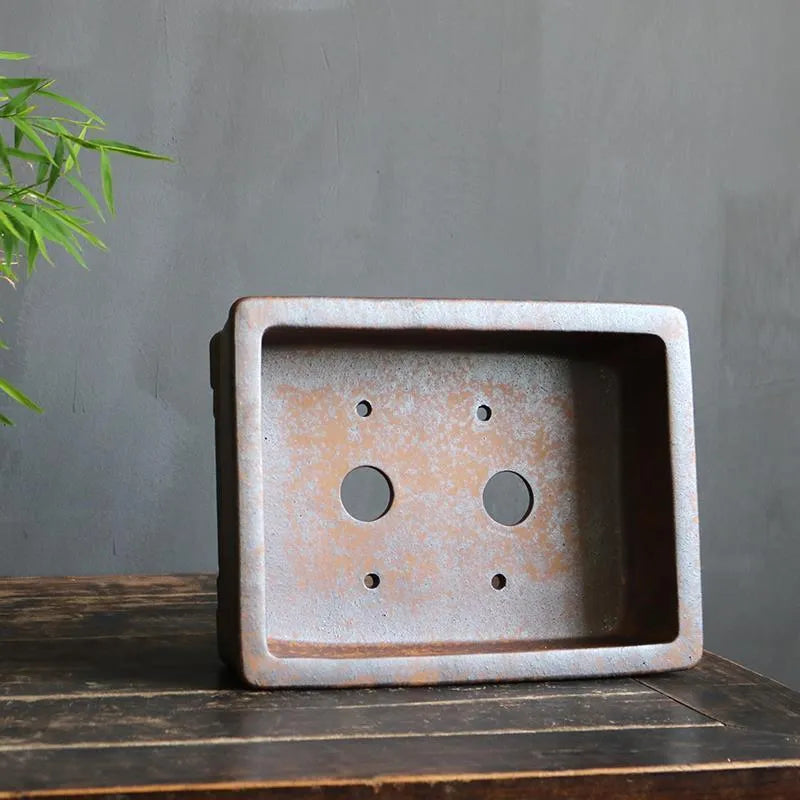 Rectangular purple sand bonsai pot with rustic firewood-burned texture, shown empty on a wooden surface.