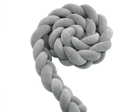 Braided knot style crib bumper in spandex velvet, wrapped around white cot rails in a nursery.