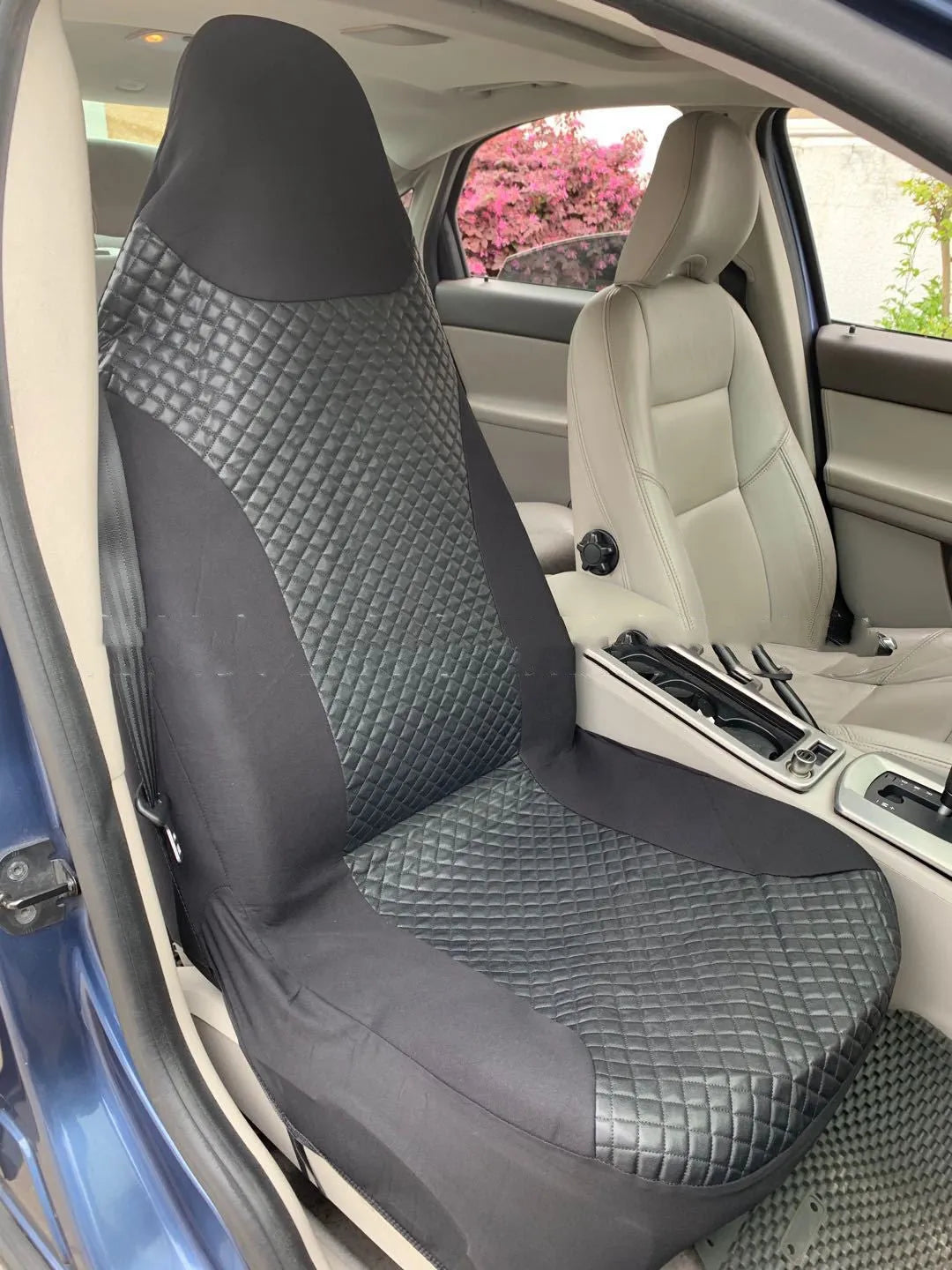 Black quilted automotive seat cover made of PU and polyester fabric with plastic attachment hooks.