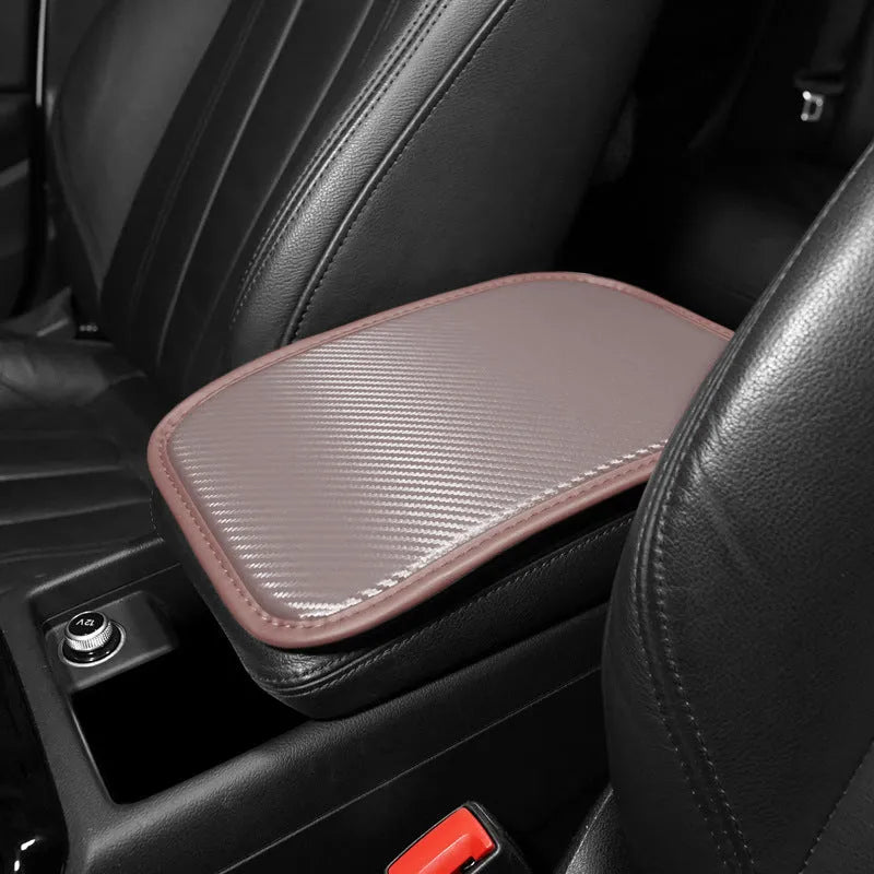 Leather car armrest cushion with carbon fibre pattern in red, shown on a car centre console.