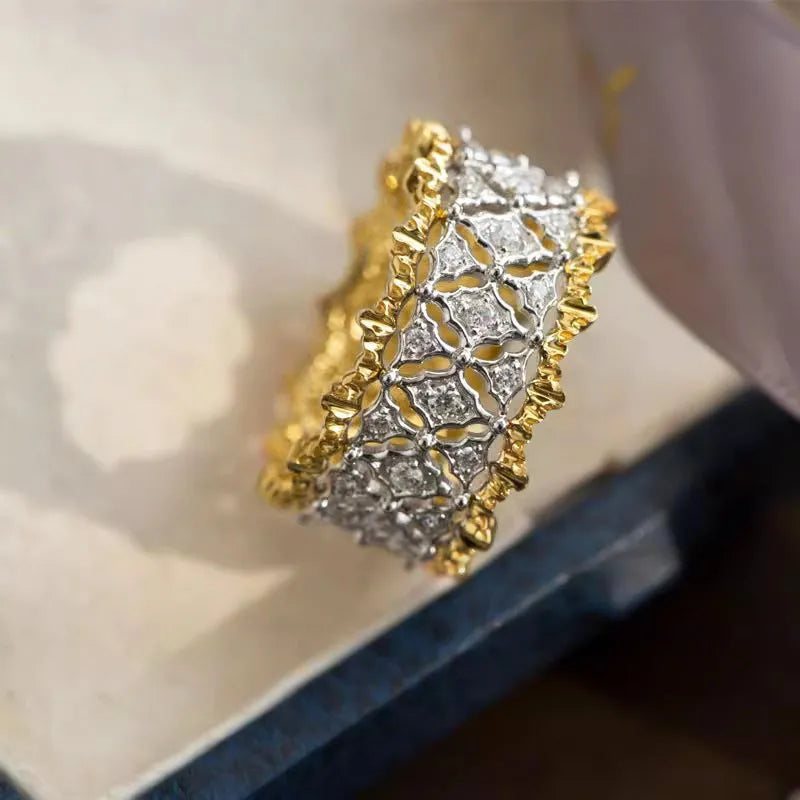A geometric two-tone gold zircon ring on a white background, showing its round centre detail and copper band.