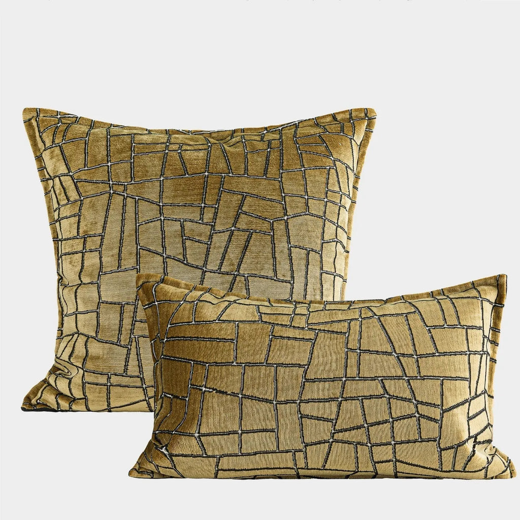 Geometric patterned cushion covers in gold colour on a grey sofa.
