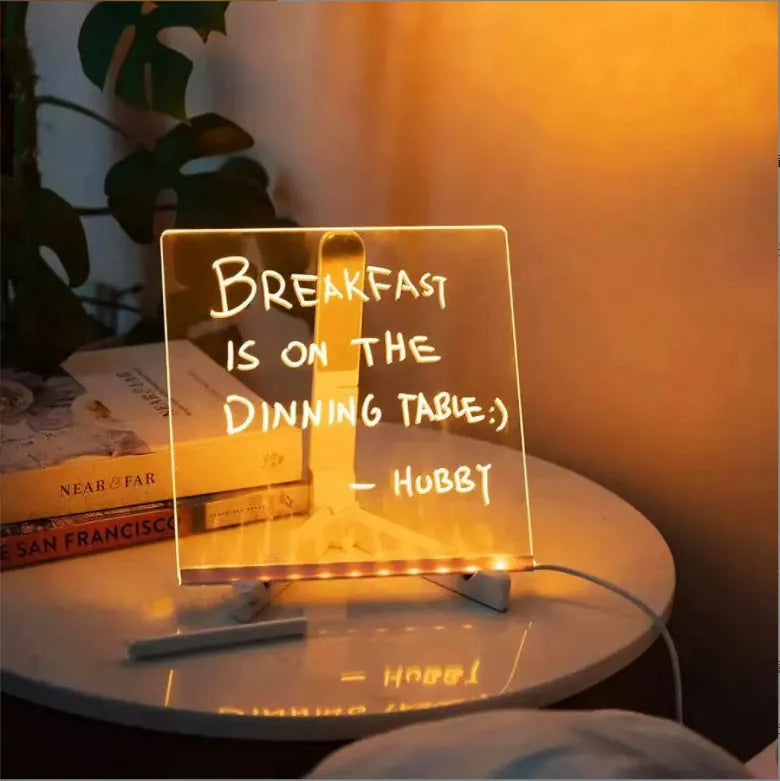 DIY acrylic LED message board on a desk with handwritten notes, glowing softly, next to colourful pens.