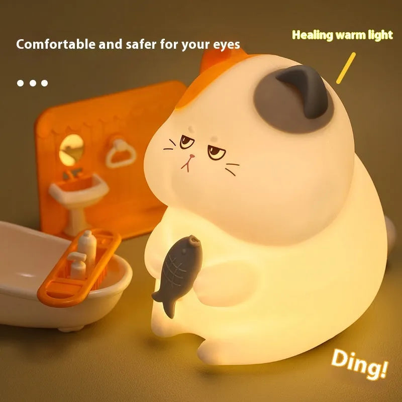 Yellow Greedy Cat cartoon desktop night light with USB cable on a wooden desk.