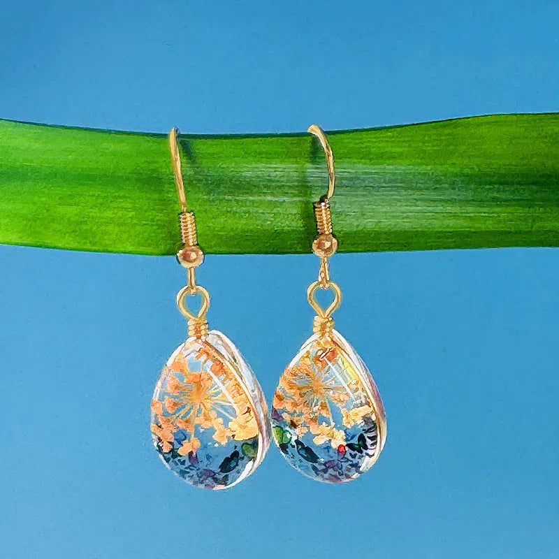 Water drop-shaped glass eardrops earrings with owl motif in ginger yellow and pink coloured glaze on a light background