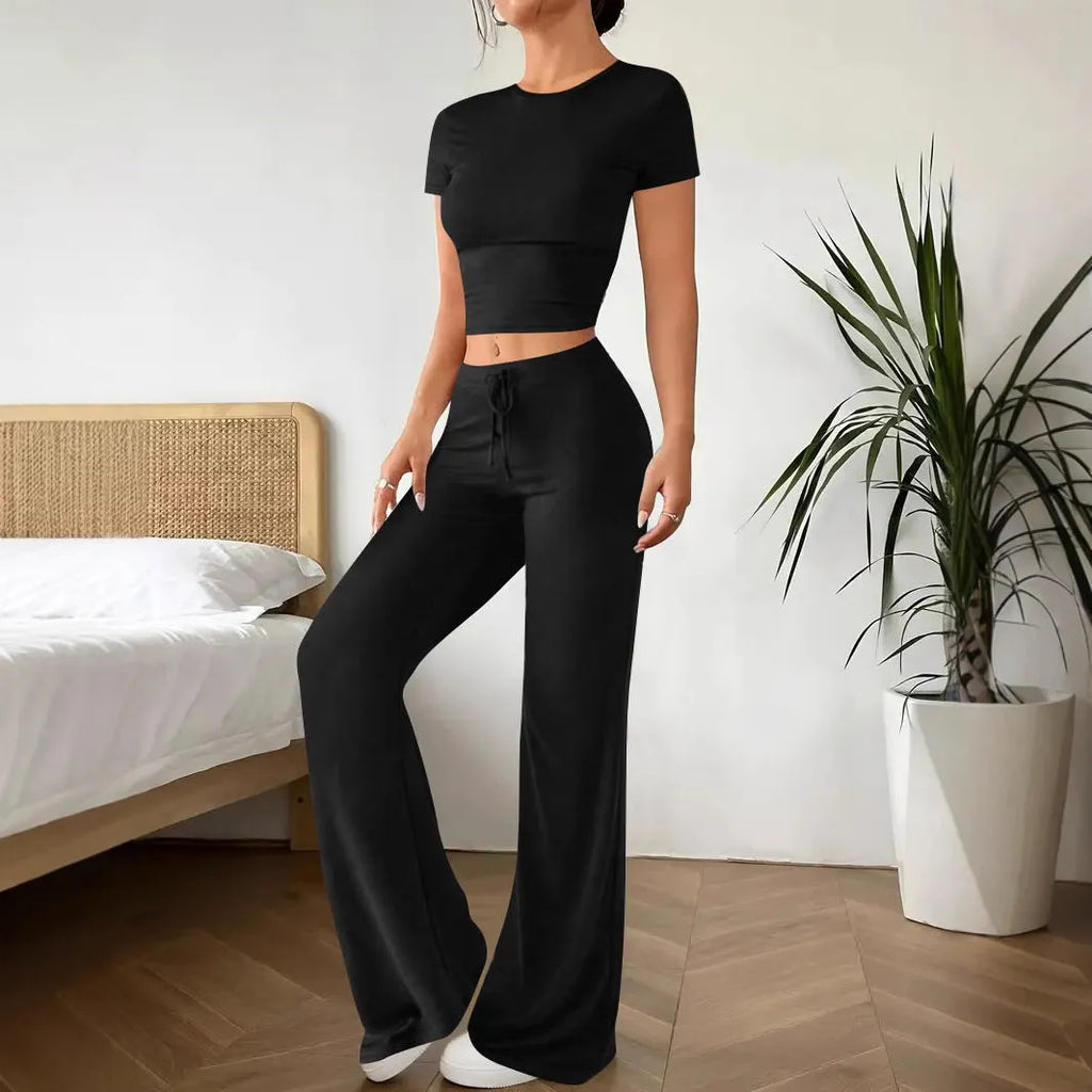 A woman's black high-waist trousers and matching short-sleeve T-shirt co-ord set laid flat.