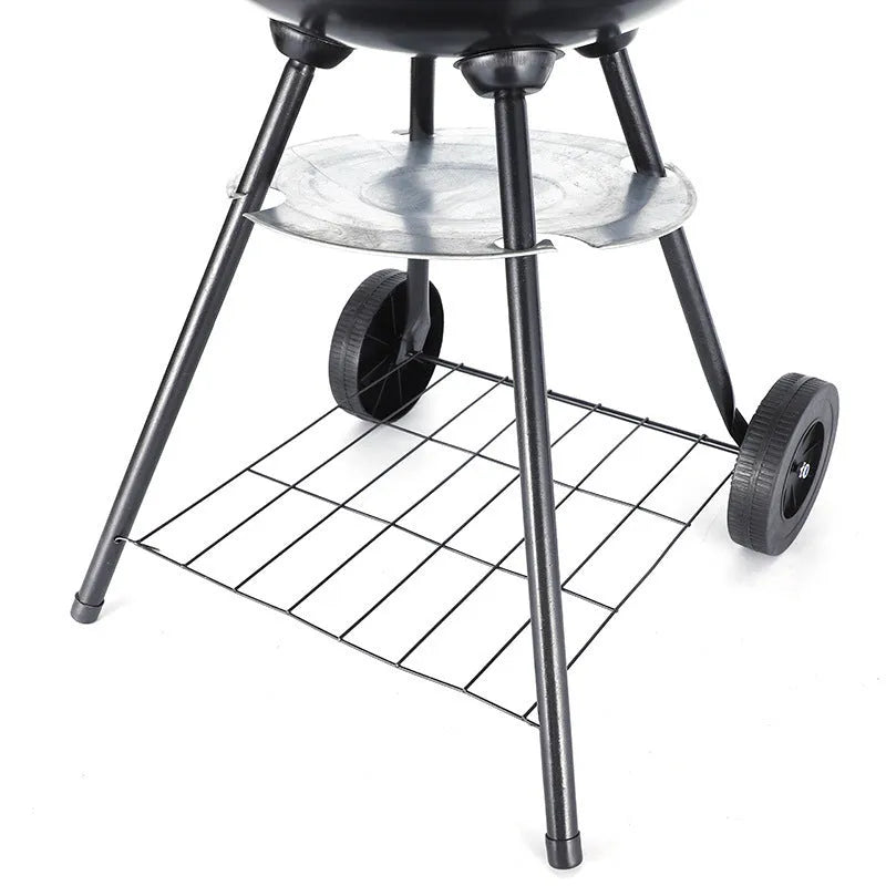 A compact, circular portable barbecue oven with a 14-inch cast iron grill grate, shown on a patio.