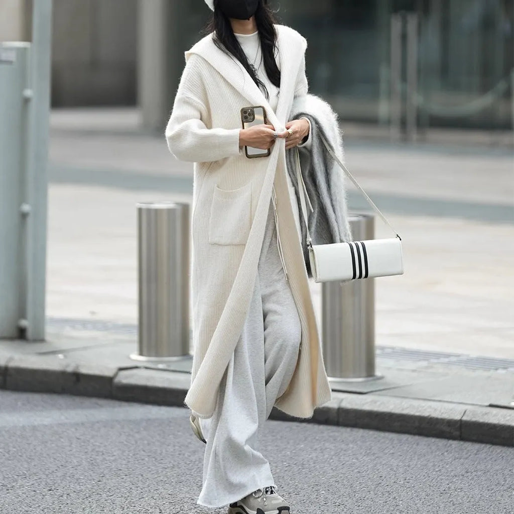Long grey knitted cardigan coat with long sleeves on a hanger.