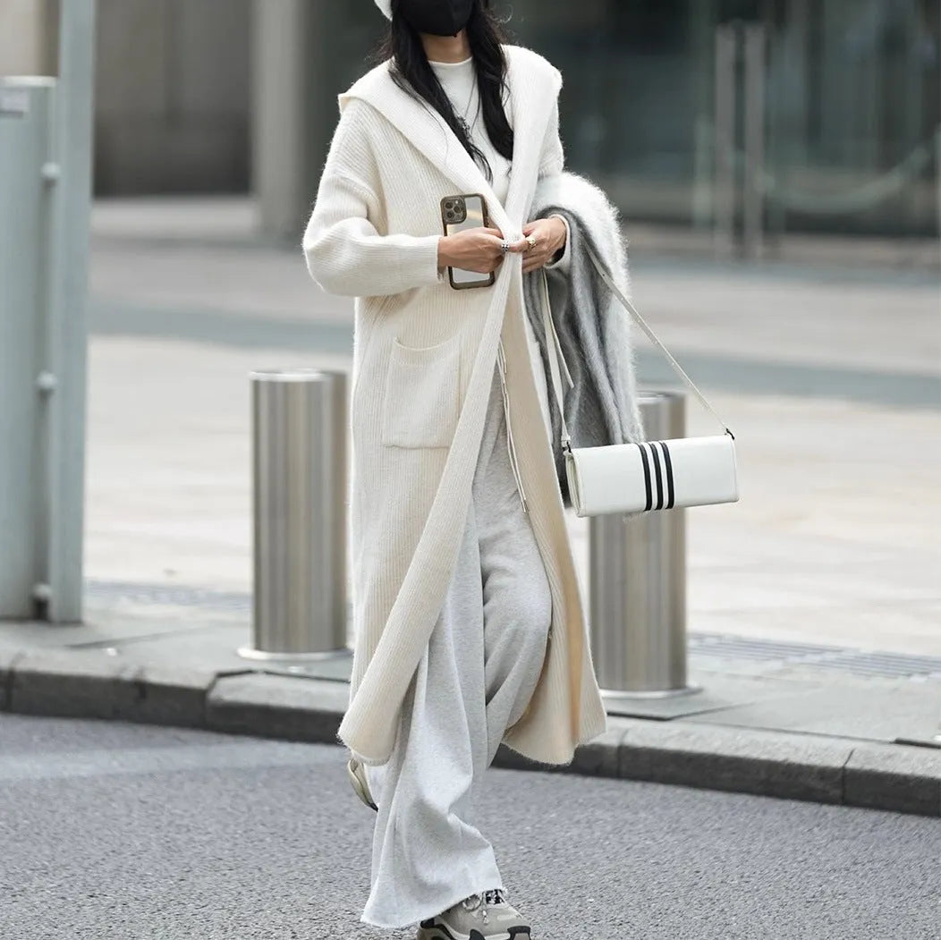 Long grey knitted cardigan coat with long sleeves on a hanger.