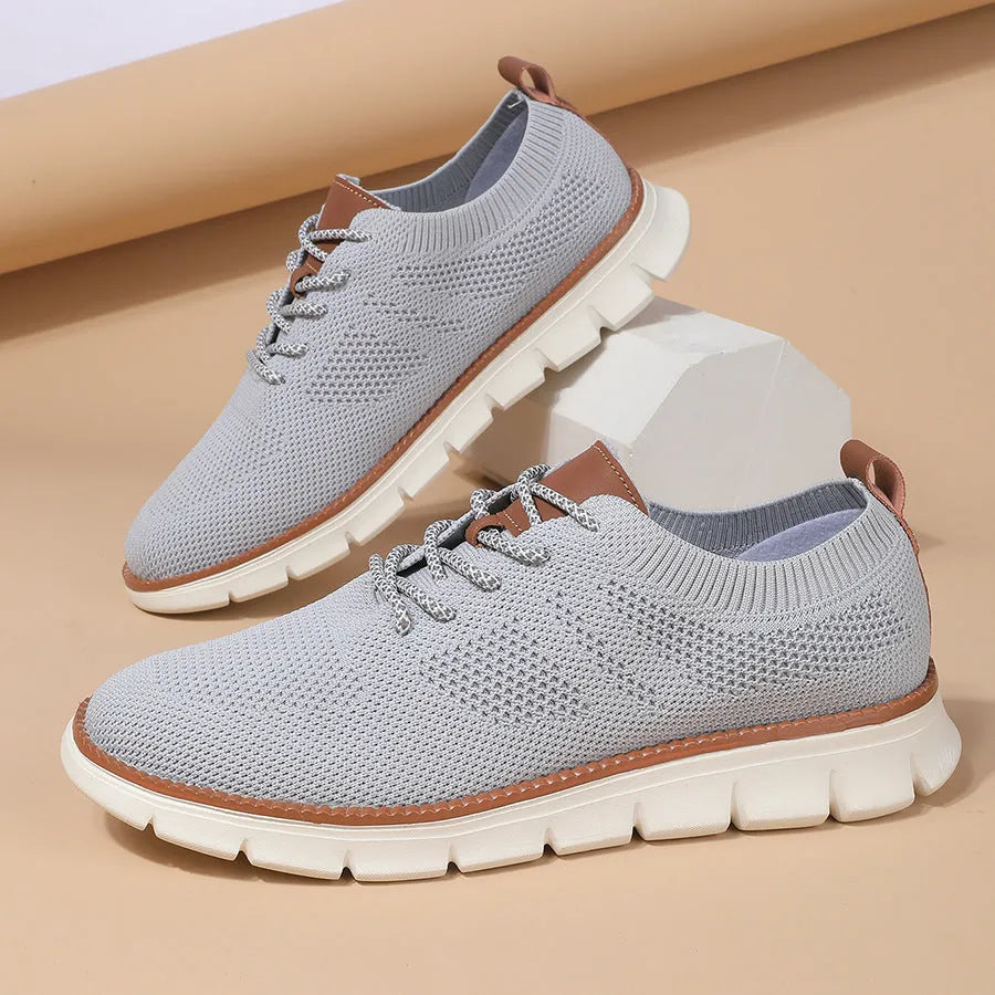 Men's grey and black mesh fabric casual sneakers with a round toe and low heel on a plain background.