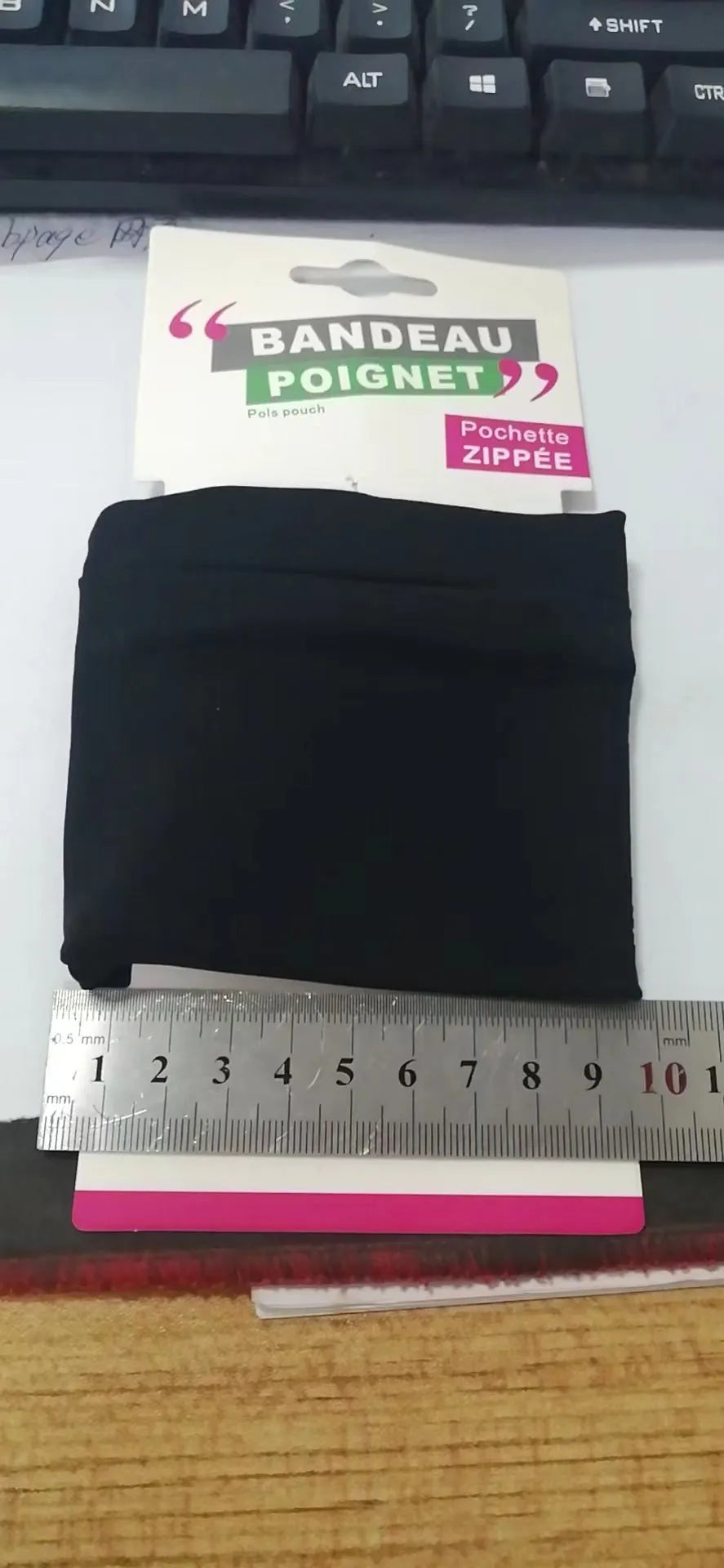 Black wrist sleeve bag with a mobile phone inserted, showing hands-free design on a person's wrist.