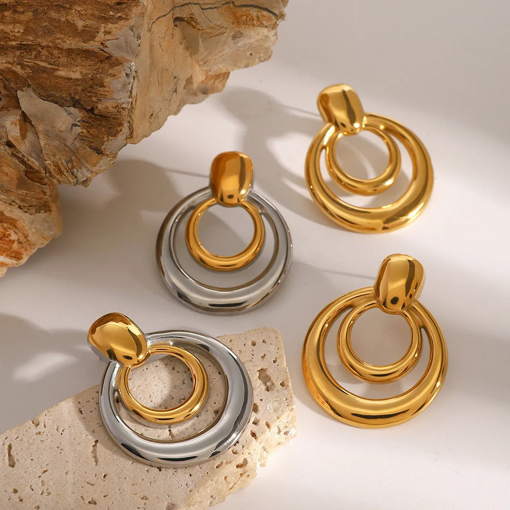 Round golden double layer hollow stud earrings with a geometric design on a white background.