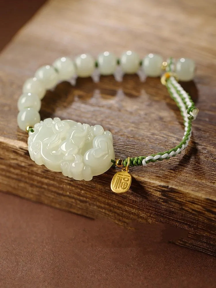 Hetian Jade Zodiac Bracelet on wrist showing rabbit charm, silver card, and red ice cotton rope.