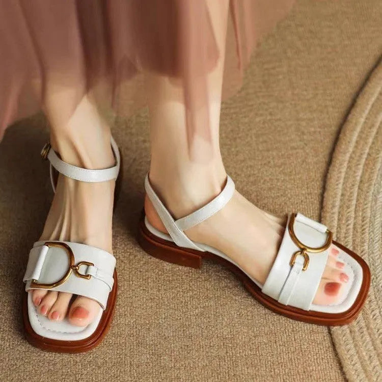 Women's black leather sandals with a thick rubber sole and a single button closure on the strap.