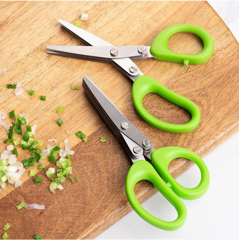Stainless steel multi-layer kitchen scissors for cutting green onions and herbs on a chopping board.