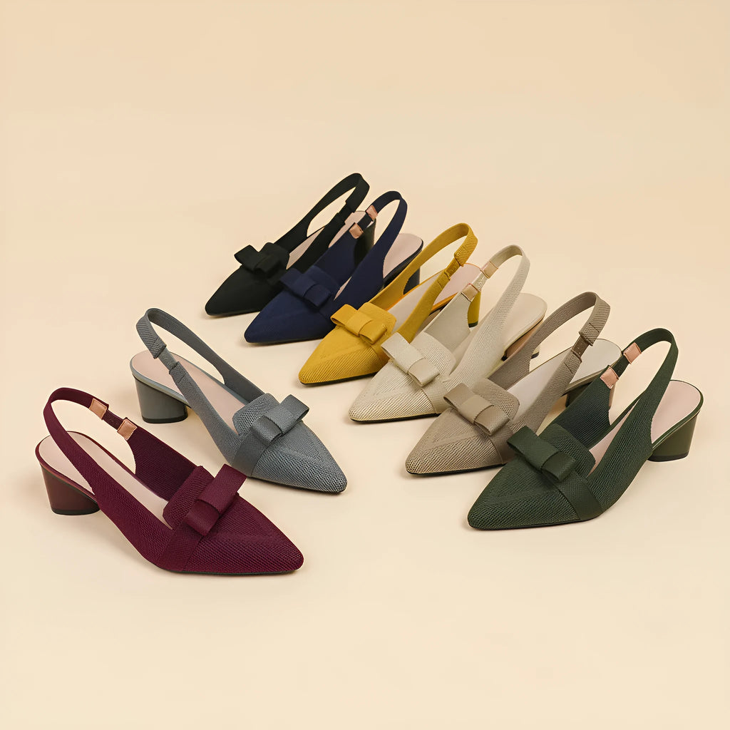 Women's black closed toe high heel sandals with a bow detail and an ankle strap on a rubber sole.