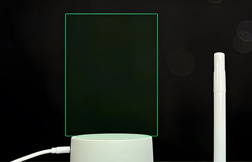 Black acrylic message board with LED lighting and remote control on wooden desk