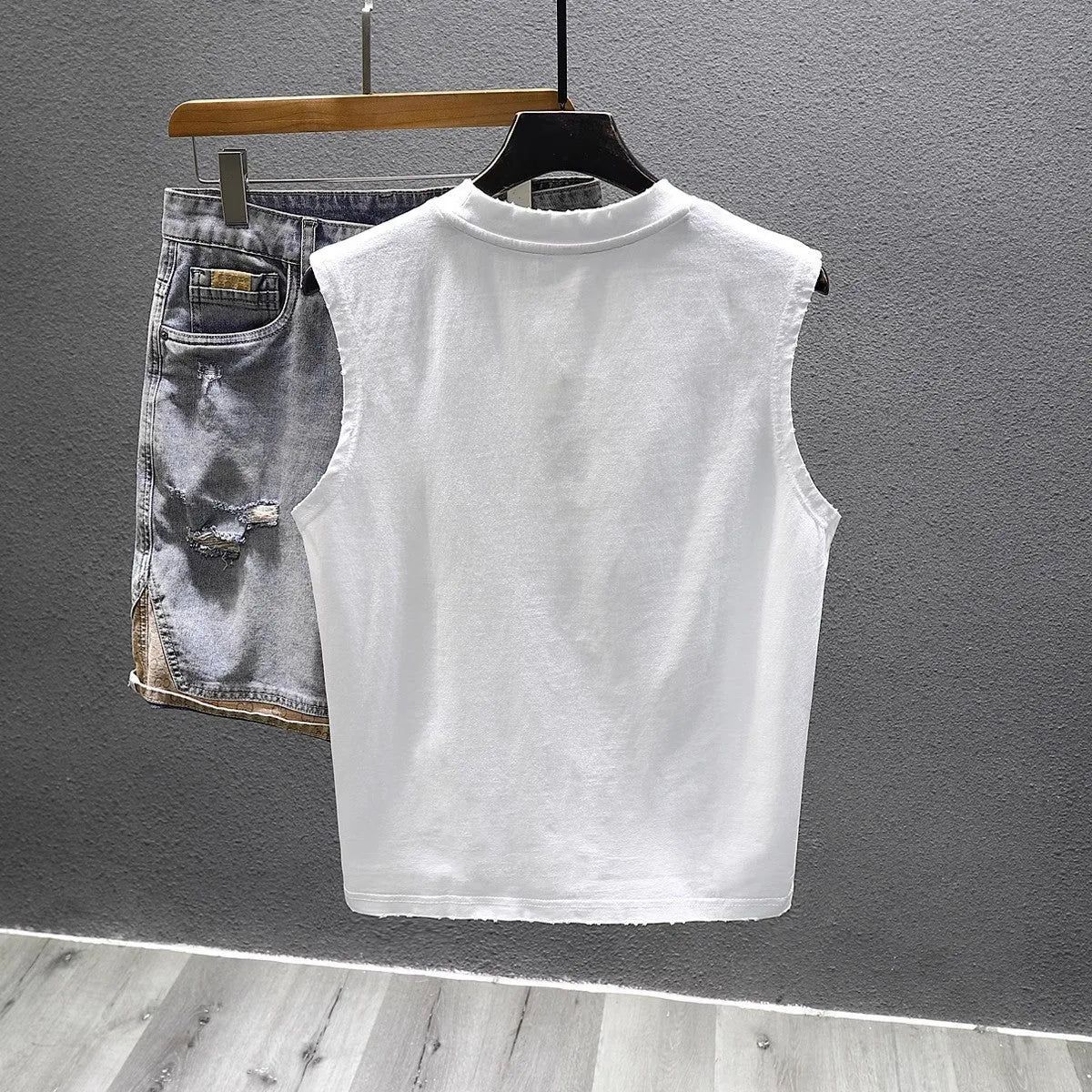 Men's loose fit black cotton sleeveless t-shirt on a hanger, showing straight hem design.