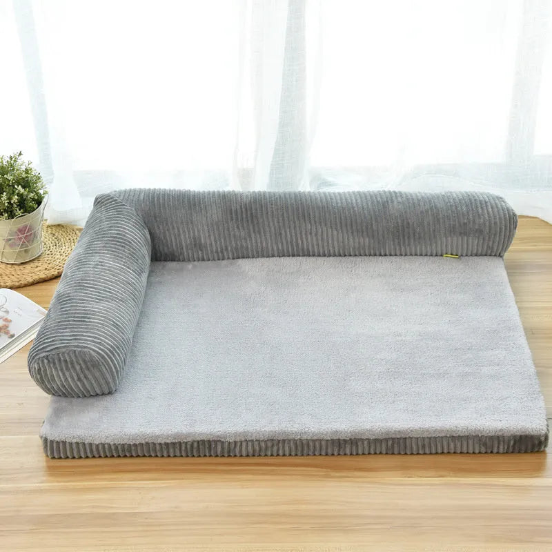 A corduroy dog sofa bed with a raised bolster side, shown in a grey colour on a wooden floor.