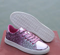 Women's black, gold, and pink sequinned low-top lace-up shoes on a white background.