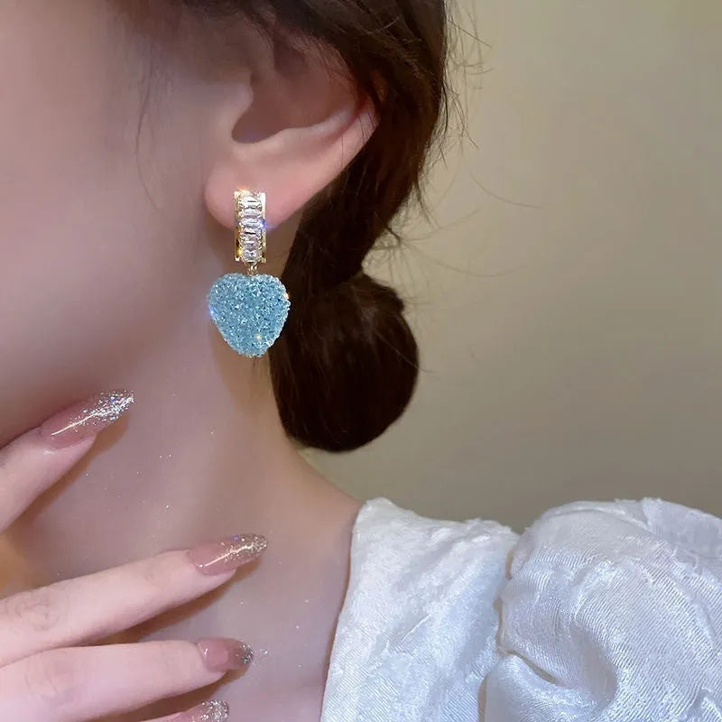 A pair of peach-shaped heart earrings with candy studs in either pink or blue colour.