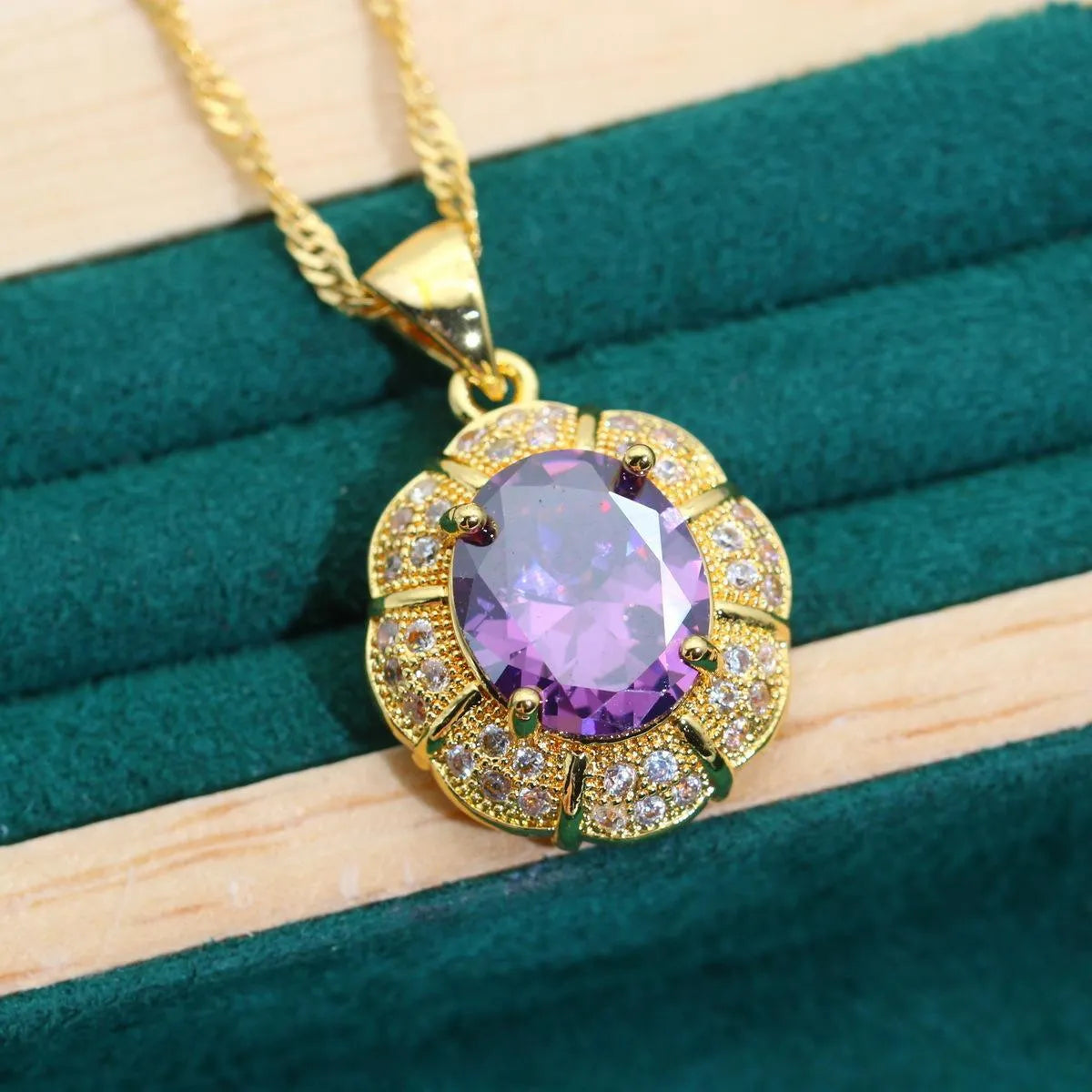 Gold jewellery set with sparkling blue cubic zirconia stones, showing necklace, earrings, ring, and bracelet on a dark background.
