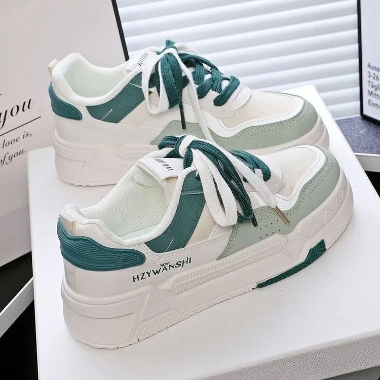 Beige children's platform trainers with cross shoulder straps and white rubber soles on a wooden floor.