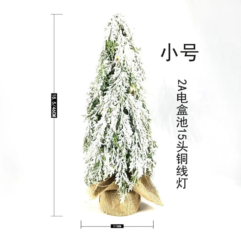 Small 24-inch white artificial Christmas tree with LED lights and snow effect on a desktop