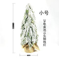 Small 24-inch white artificial Christmas tree with LED lights and snow effect on a desktop