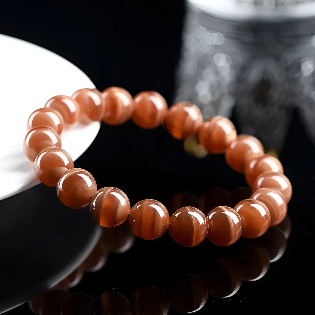 Natural Old Mine Rhodochrosite mineral bracelet with round beads in 6mm or 8mm size on a wrist.