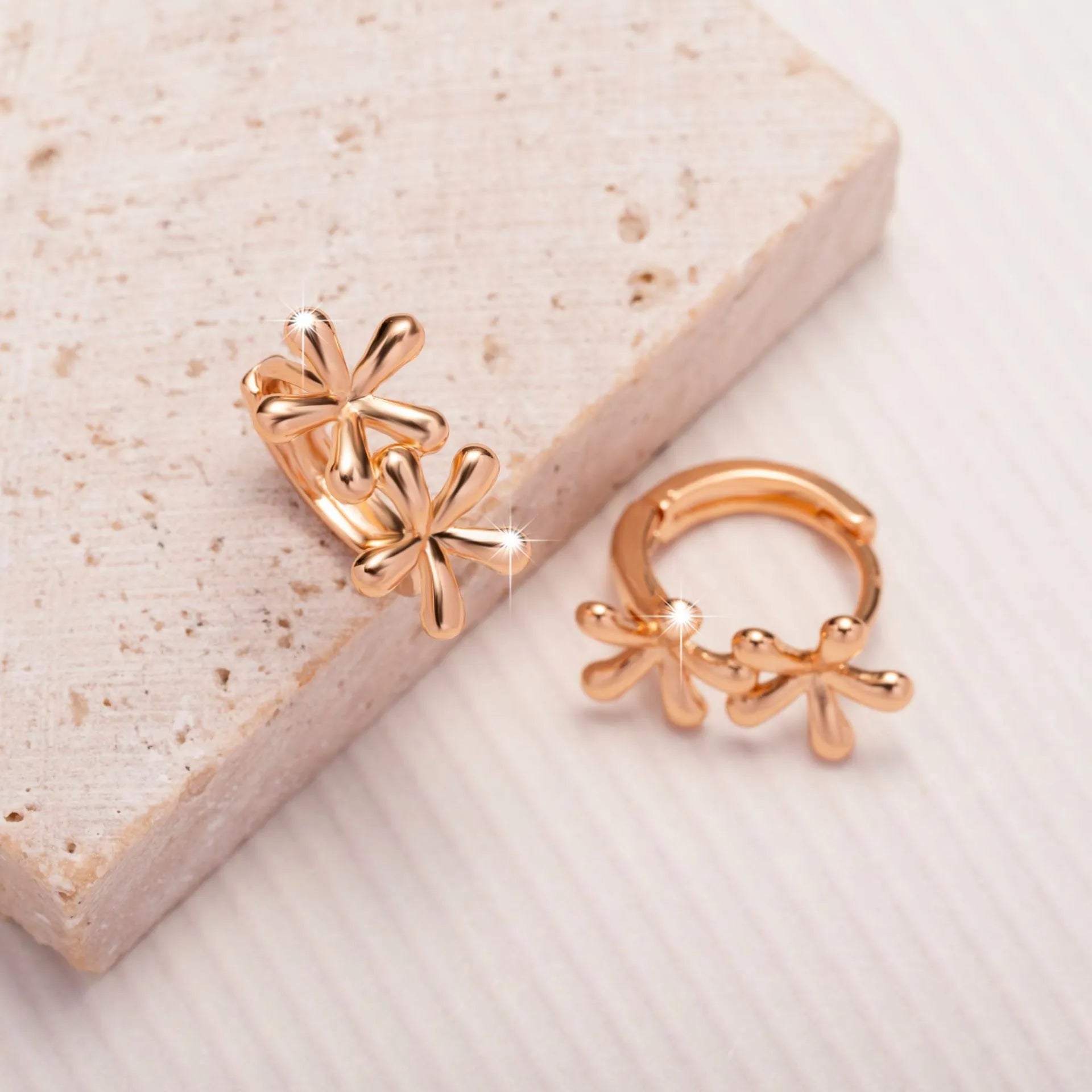 Rose gold circular waterdrop flower earrings with sterling silver posts on a white background.