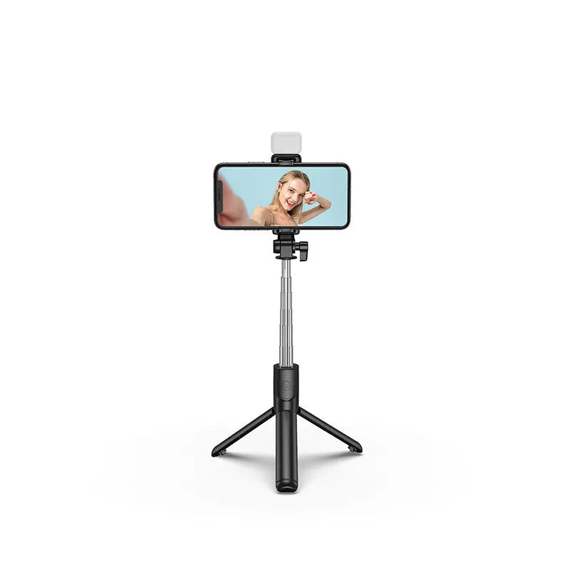 Black Bluetooth selfie stick with extended tripod legs and integrated fill light, holding a smartphone.