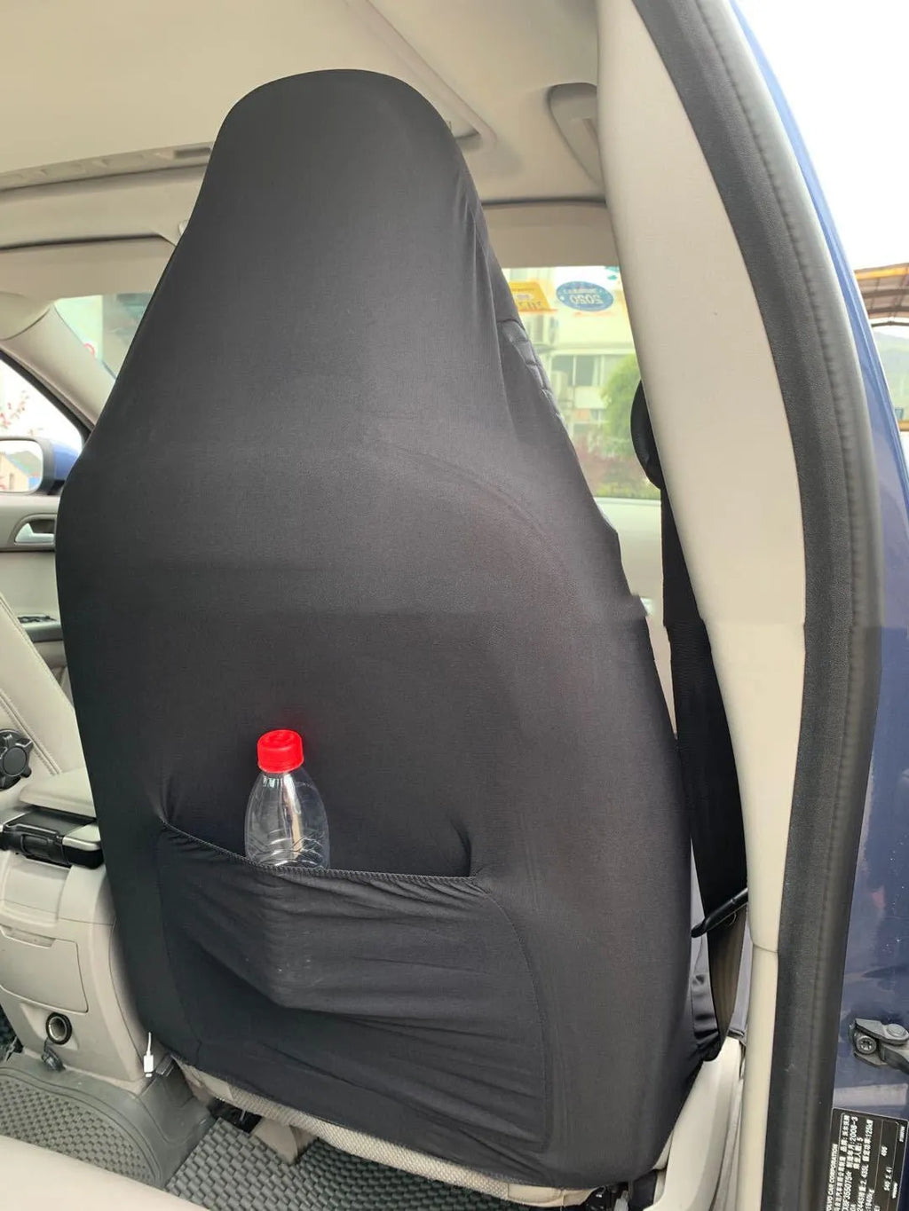 Black quilted automotive seat cover made of PU and polyester fabric with plastic attachment hooks.